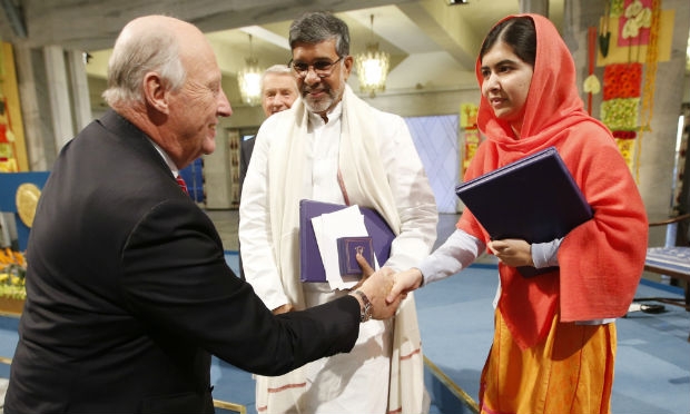 Malala e o indiano Kailash Satyarthi, que dividiram o Nobel da Paz este ano, são cumprimentados pelo Rei Haroldo da Noruega.  / Foto: Heiko Jungle / AFP