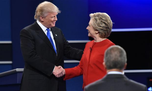 Clinton veste um tailleur vermelho e Trump está com terno escuro e gravata azul / Foto: AFP
