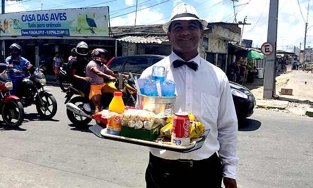 Ailton Manuel oferece seus produtos em uma bandeja para servir os clientes no meio da rua / Foto: Priscila Miranda/NE10