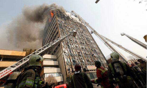 Minutos antes de desabar, bombeiros tentavam apagar o fogo que se espalhou pelo prédio em Teerã / Foto: AFP
