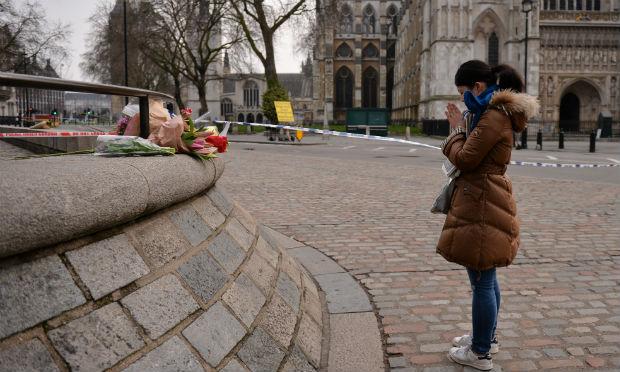 Mulher reza em frente à homenagens deixadas pelos britânicos nas proximidades do Parlamento britânico. / Foto: JUSTIN TALLIS / AFP